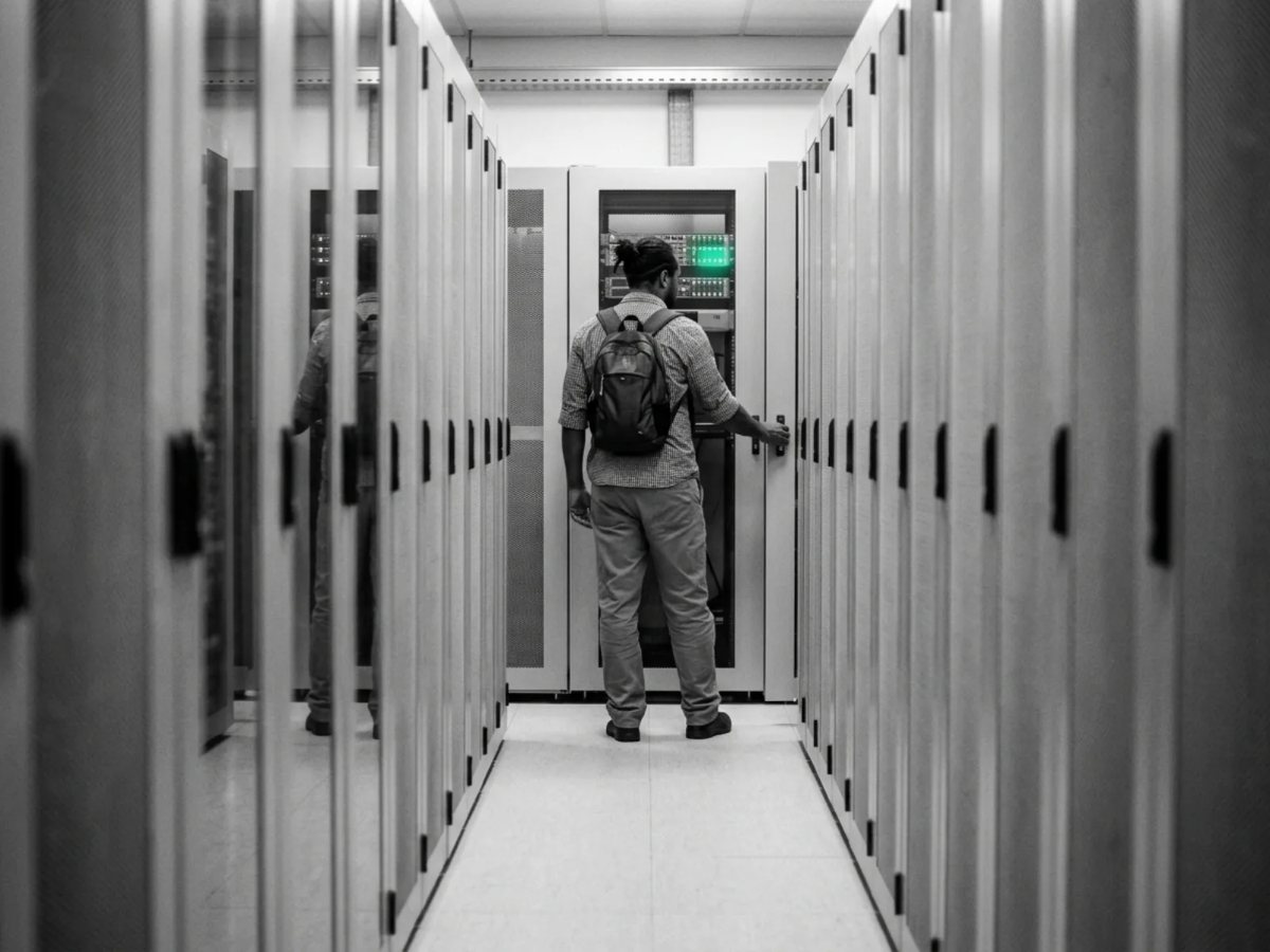 A technician closing a rack door at the end of a quiet data centre aisle